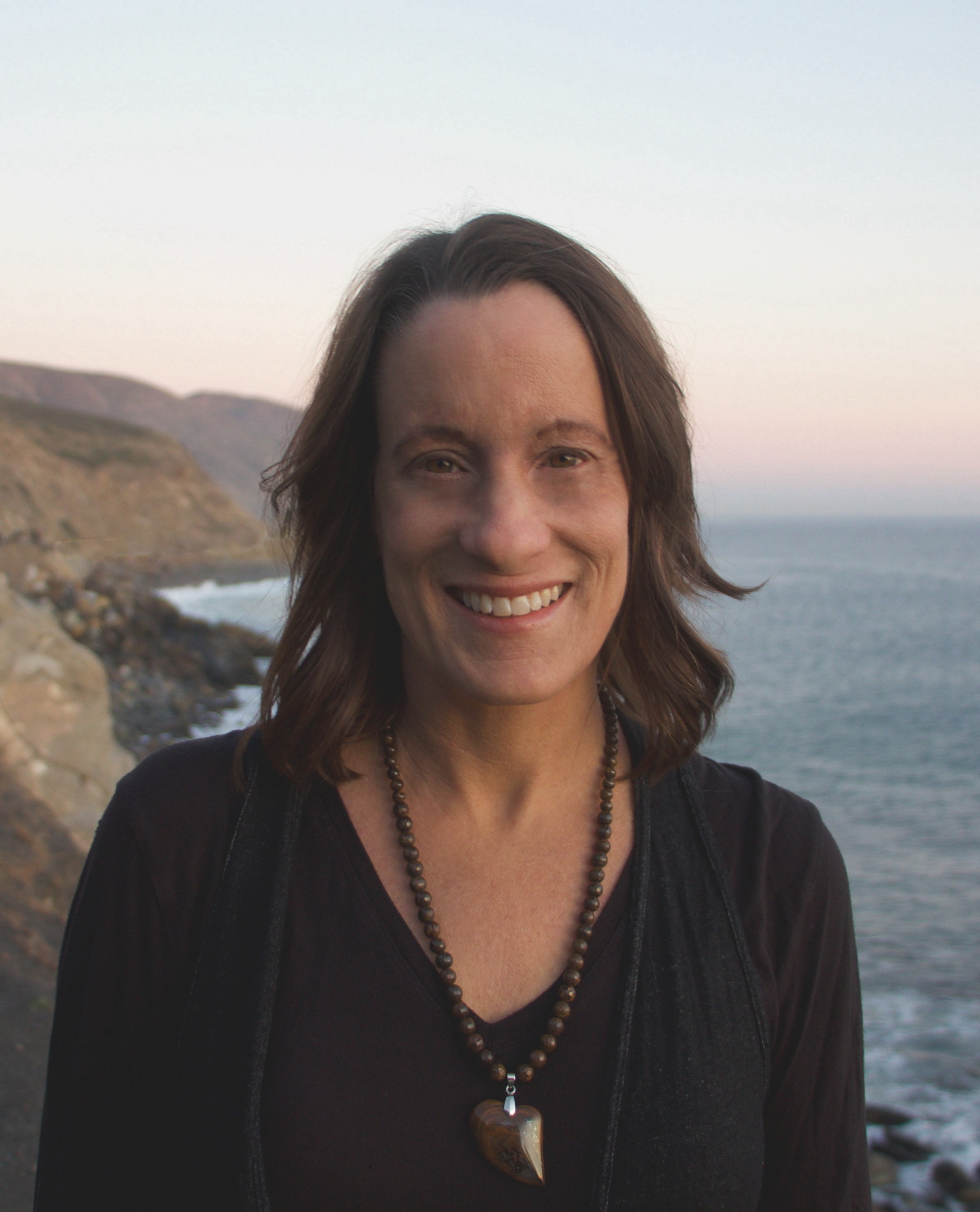 Cindy Costley in black, with coastal cliffs behind her